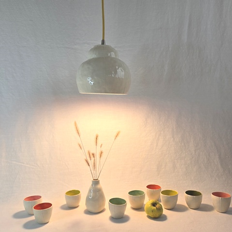 bubble pendant lamp over group of scolorful sake cups and bud vase with grass